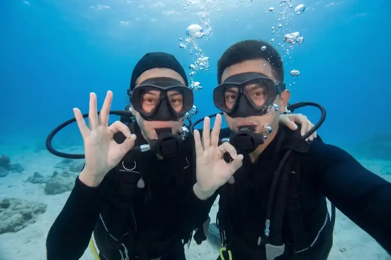 A professional dive buddy assisting scuba divers with Seaweed Village in the Semporna Islands area.